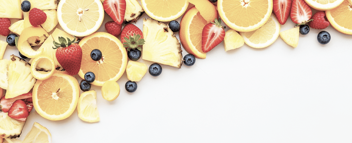 A colorful assortment of fresh fruits arranged along the top and right edges of a white background